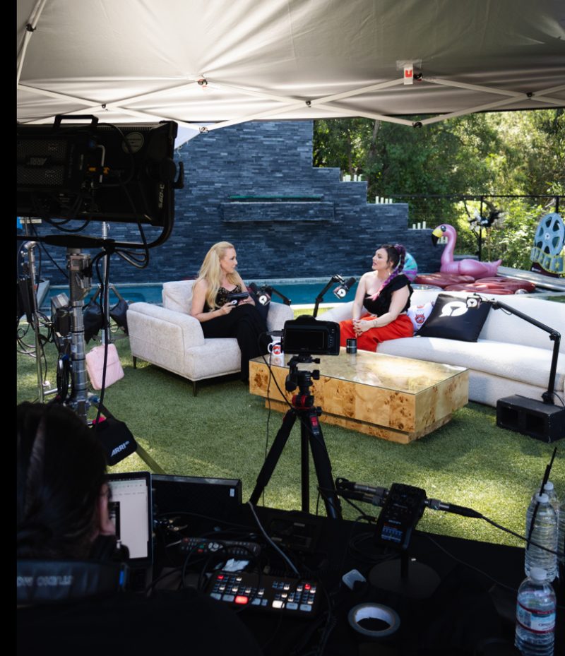 The outdoor podcast set at the house: white couches under a canopy by the pool