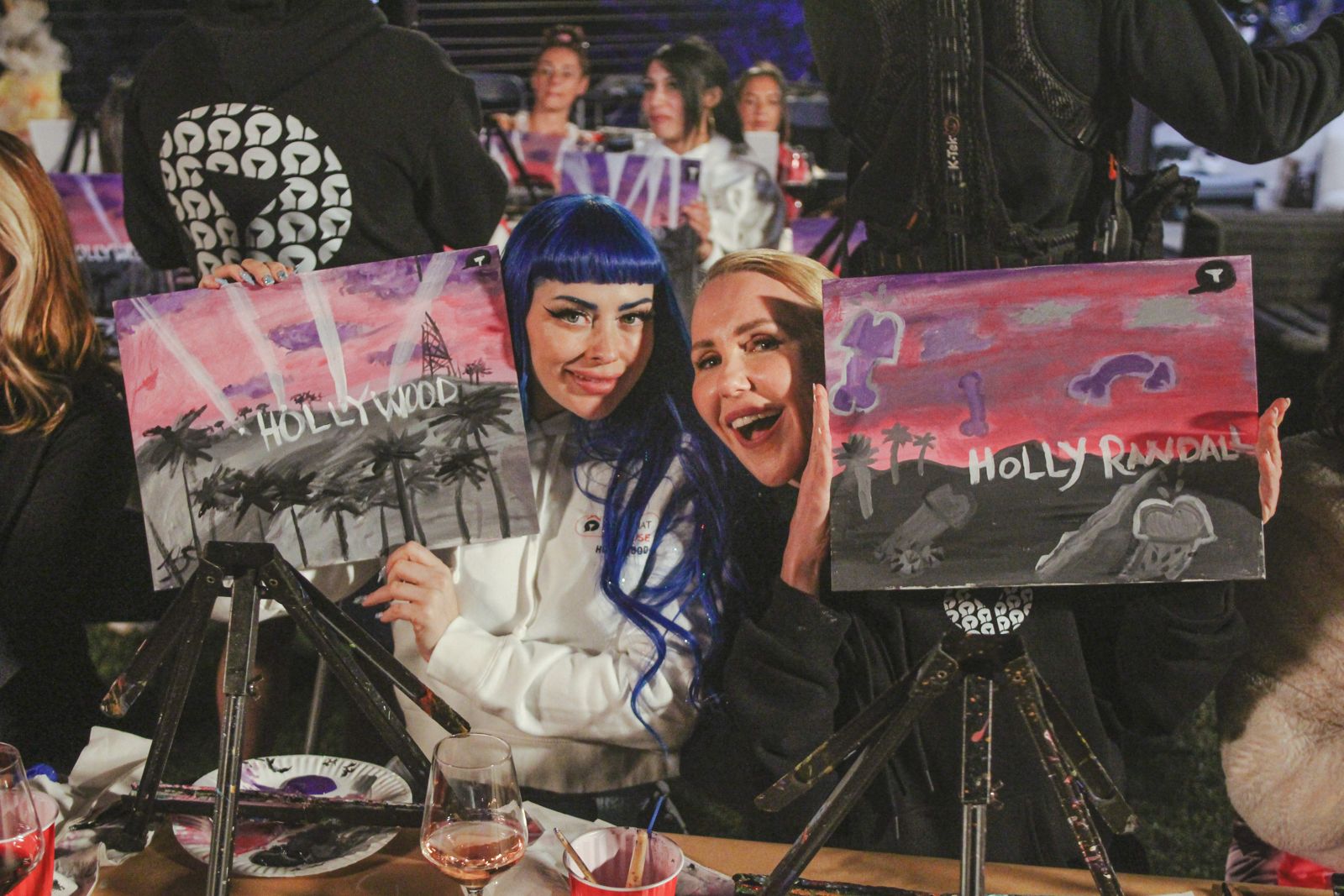 A cast member shows off her painted Holly Randall canvas at the Stripchat House sip and paint night