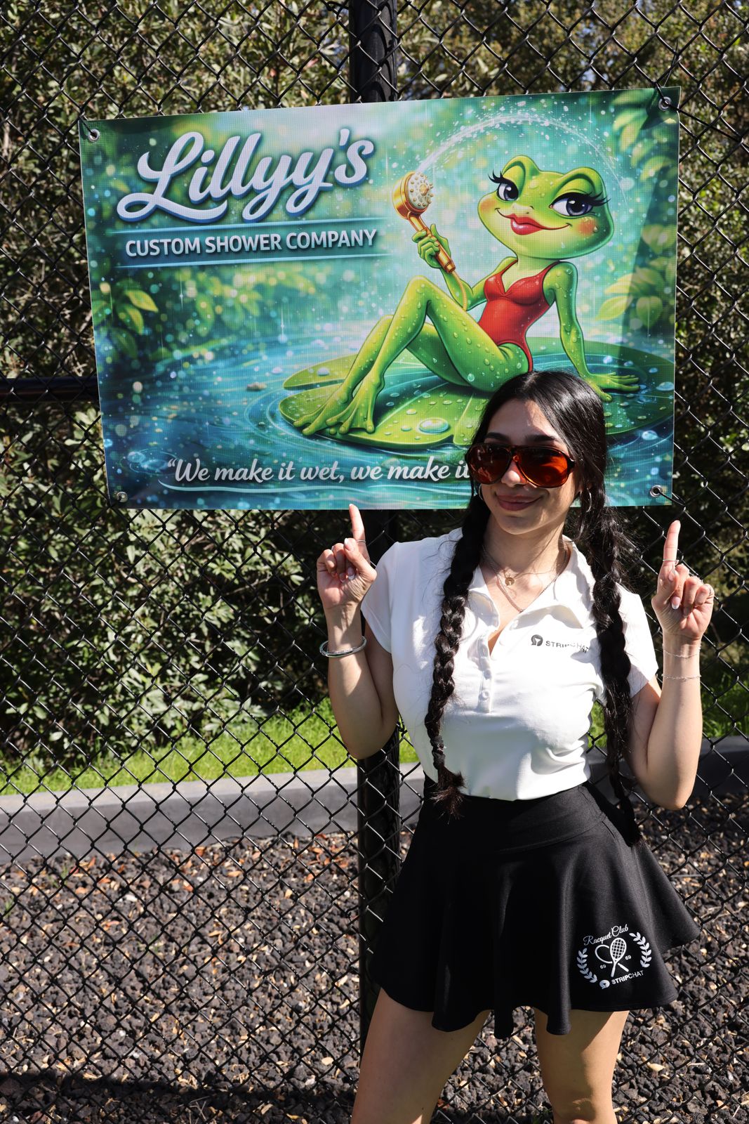A cast member poses with her parody sponsor banner at the Stripchat House pickleball tournament