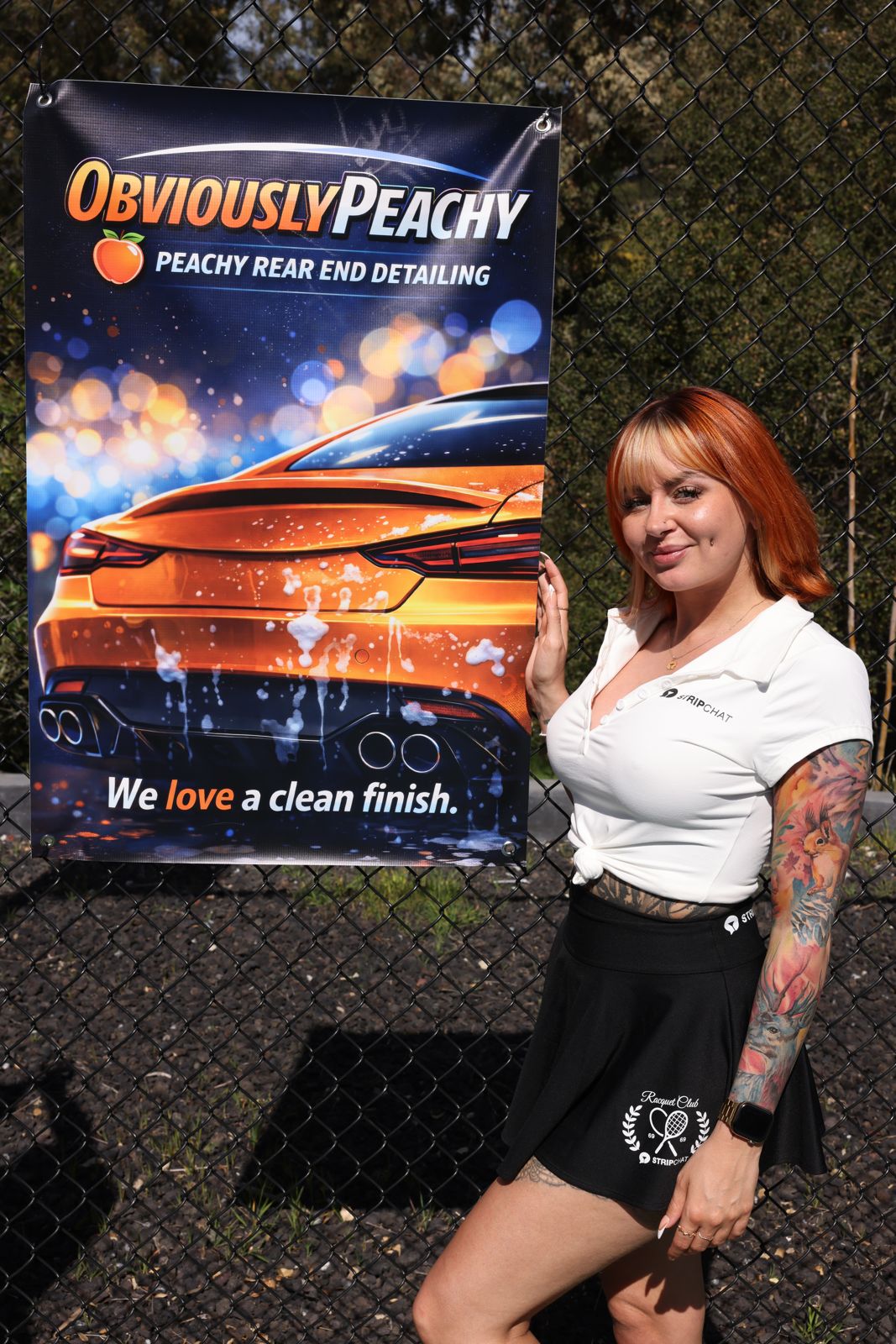 A cast member poses with her parody sponsor banner at the Stripchat House pickleball tournament