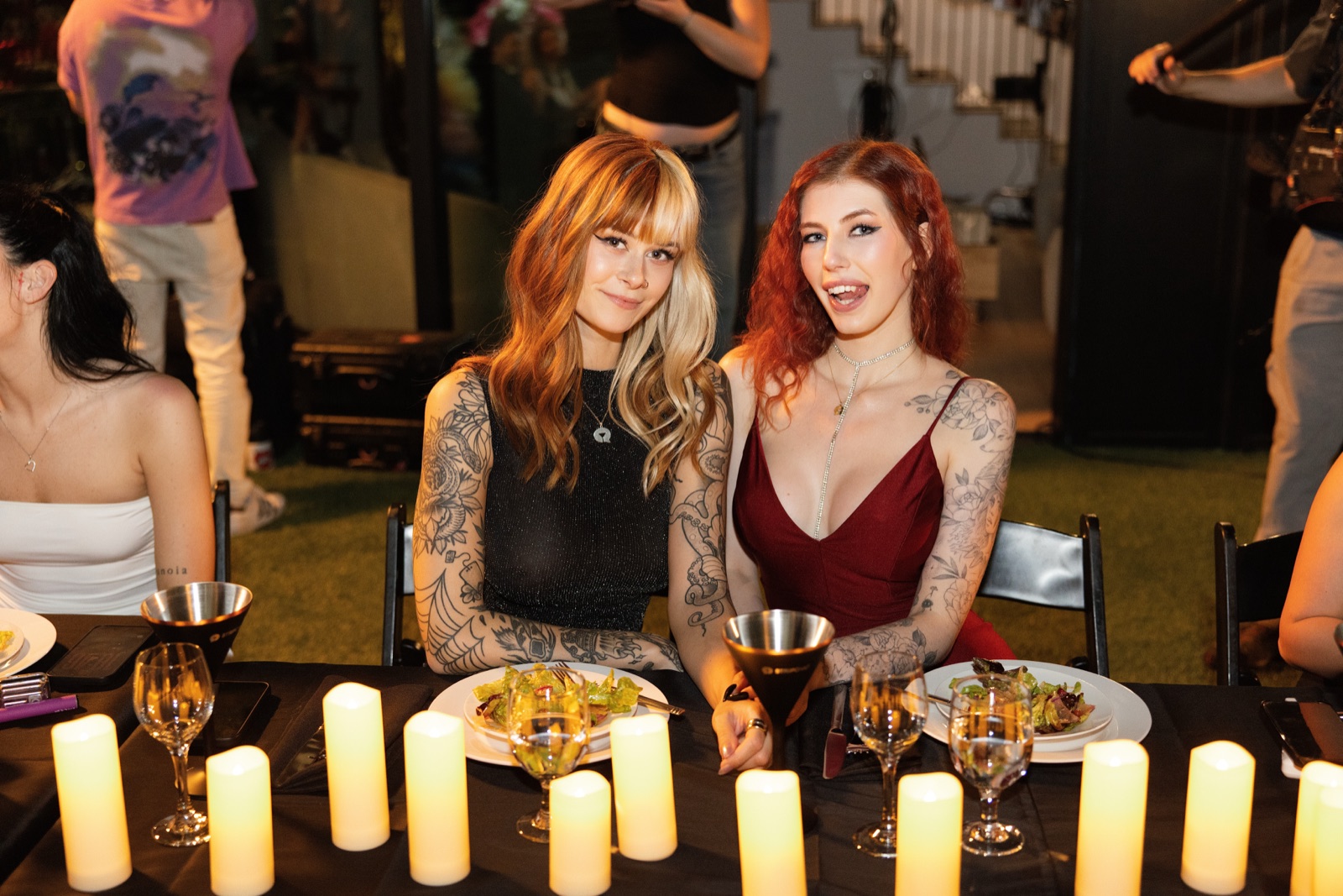 Two redheaded guests laugh together over dinner plates and candles