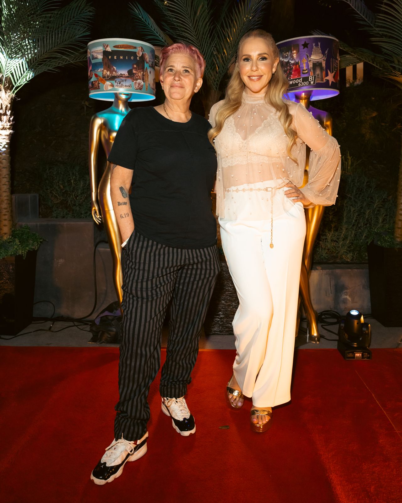 Party guests pose with the gold mannequin installation at the Stripchat House Hollywood launch party
